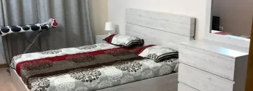 تخت خواب با روتختی قهوه ای و میز آرایش قهوه ای رنگ در اتاق خواب آپارتمان در 40دستگاه