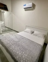 تخت خواب با روتختی سفید و کمد دیواری اتاق خواب آپارتمان در ششصددستگاه