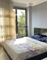 تخت خواب با روتختی سرمه ای رنگ و پنجره رو به محوطه اتاق خواب آپارتمان در کیش