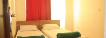 دو تخت خواب با روتختی سفید و پرده قرمز اتاق خواب ویلا در شهرک ششصددستگاه