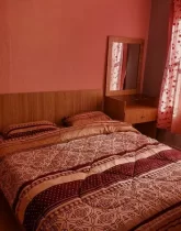 تخت خواب با روتختی قهوه ای و پرده قرمز اتاق خواب ویلا در شهرک میرمهنا
